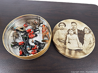 Photo showing the round tin box with lid featuring sepia family photo and several toy soldiers inside