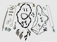 Full view of the assorted costume jewelry laid out, showing necklaces, earrings, bracelets, and brooches in black and metallic tones.