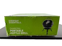 Box front showing the Everyday Essentials brand, product type as portable charcoal kettle grill, and an image of the black kettle grill with legs and lid.