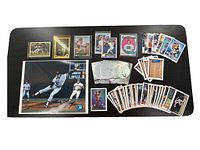 Overall view of collection including signed photo with multiple baseball cards and other sports cards on table.