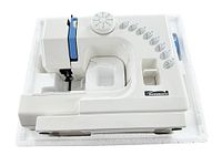 White and blue Kenmore sewing machine resting on white foam packaging. Compact, with dials and stitch pattern icons visible.
