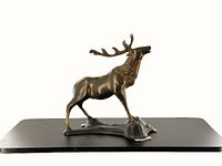 Side view of the vintage cast metal stag statue showing its detailed antlers, muscular body, and textured mane on a sculpted base with felt pads.
