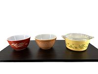 Front view of three vintage Pyrex items arranged side by side: two mixing bowls and one lidded casserole dish