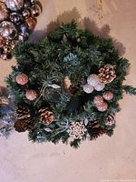 Photo showing artificial pine wreath decorated with pinecones and glittery pinecone and snowflake ornaments