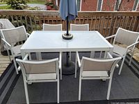 Full view of patio table with six chairs and umbrella on outdoor rug