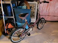 Full angle view of Schwinn foldable bicycle showing maroon frame, saddle, rear rack, and front wheel.