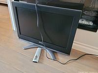 Small Toshiba flat-screen TV with stand and remote placed on floor