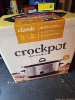 Photo of the Crock-Pot box highlighting product details including 7 quart oval capacity, 3 heat settings, manual warm setting, and suitability for 9+ people.