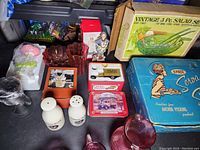 Overview of the vintage and miscellaneous home decor items including glass pieces, tins, salt and pepper shakers, and a boxed salad set.