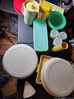 Top view showing all Tupperware items arranged together including the large round bases, rectangular green container, yellow cups, and small triangular container.
