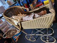 Side view of the vintage wicker baby carriage with fabric lining and metal frame with wheels.