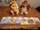 Photo showing Teddy Ruxpin doll, a smaller companion plush toy, and six children's storybooks on a table.