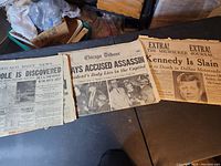 Three vintage newspapers with headlines related to Kennedy assassination