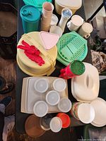 Wide view of multiple vintage Tupperware items including containers, pitchers, and a cake carrier