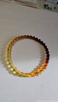 Full view of the circular amber bracelet showing color gradient from light yellow to dark brown beads.
