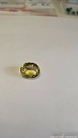 Oval-shaped lemon citrine gemstone on a white background showing its size, color, and cut.