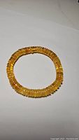 Front view of golden amber bracelet on white background showing translucent amber beads.