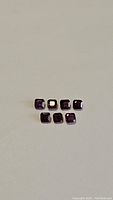 Overhead view of seven octagon cut red gemstones on plain background