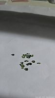 Overview of small oval and round faceted yellow-green sapphires placed on white background in sunlight, showing their color and clarity.