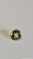 Single round lemon citrine gemstone showing diamond checkerboard cut facets and yellow-green color under lighting.