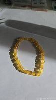 Photo showing elastic bracelet of polished golden Baltic amber nuggets in a slightly oval shape, reflecting natural light.