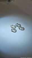 Parcel of four round green amethyst gemstones with checkerboard button cut visible, arranged on a white surface with lighting highlighting stone facets and color.