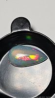 Pear-shaped Ethiopian opal cabochon showing vibrant orange and red fire with green highlights.