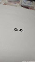 Two small pear-shaped off-white aquamarine gemstones, displayed on plain white background, showing size and shape