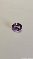 Photo of the purple pink amethyst gemstone, oval cut, showing its color and clarity