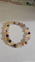 Photo showing natural purple fluorite and yellow agate bead stretchy bracelet, arranged in a circle on white background with visible bead colors and patterns
