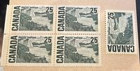 Five Canadian 25 cent postage stamps including a block of four and one single, displayed on a beige surface showing details and condition.