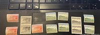 Multiple proof stamps from Newfoundland, Canada including orange, grey, green color variants and black 20 cent stamps laid out on a keyboard.