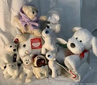 Group of various white plush toys including How to Train Your Dragons dragons, Ty Beanie Bears and Coca Cola Polar Bear, all arranged on a flat surface.