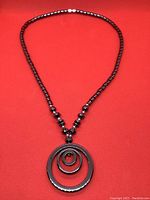 Full view of hematite necklace with the circular triple ring pendant centered, showcasing bead style and pendant design.