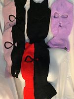 Five ski masks laid flat showing various colors and eye/mouth openings, including black/red, pink/black, solid black, and purple. No horns on any masks.