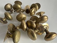 Photo shows twelve antique brass domed buttons with screw-back mountings arranged on a flat surface.