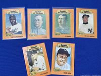 Seven classic baseball cards shown face-up displaying player portraits and names including Jackie Robinson, Ty Cobb, Cy Young, Mickey Mantle, Lou Gehrig, Babe Ruth, and Denton 'Cy' Young.