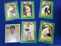 Front of 6 assorted classic baseball cards with green borders featuring Bob Feller, Joe DiMaggio, Yogi Berra, Napoleon Lajoie, Willie Mays, Mickey Mantle on blue background