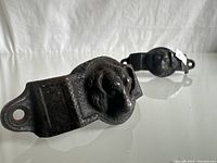 View of a black cabinet cup pull showing the central bulldog face detail, matte black finish, and mounting holes on each end.