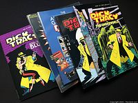 Photo showing front covers of six Dick Tracy comic books and collectible guides fanned out, featuring various action and crime scenes with Dick Tracy character in yellow coat.