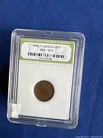 Photo of early Lincoln cent penny encapsulated in plastic holder labeled 'International Numismatic Bureau Early Lincoln Cent 1909-1919' showing obverse side of coin.