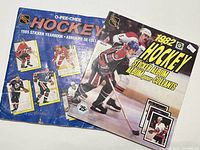 Photo showing two NHL hockey sticker albums from 1982 and 1985 with hockey player images on the covers.