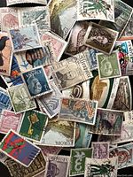Top view showing front of assorted stamps, various images including portraits, landscapes, animals, and symbols. Stamps from Spain and other countries visible.