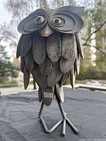 Close-up side angle of the metal owl garden sculpture showing detailed feathers, large round eyes, and legs.