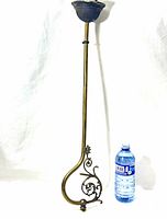 Full view of antique brass nozzle piece next to water bottle for scale