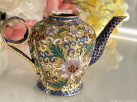 Front and side angle of the miniature cloisonne enamel teapot showing floral designs and handle.