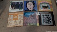 Photo showing six vinyl records titled Van Morrison and The Chieftains, Leonard Cohen, Magical Mystery Tour by The Beatles, Fairport Convention Full House, John Cale British Folk Rock, and Captain Beefheart and His Magic Band arrayed on carpet.
