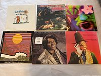 Photo of 6 vinyl records laid on table: Edie Brickell & New Bohemians, Bow Wow Wow, Arthur Brown, James Brown Gravity, Captain Beefheart Trout Mask Replica