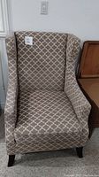 Front view of the wingback chair showing the pattern, winged sides, and seat cushion.
