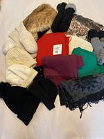 Overview of winter hats, scarves, and mittens in various colors and materials laid out on a white surface.